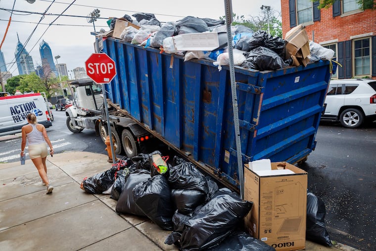 An overflowing dumpster at a garbage drop-off site at S. 18th Street and Catharine Street is removed Wednesday morning.