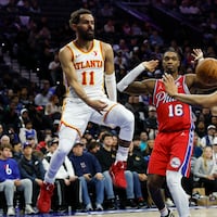 Hawks guard Trae Young passes the basketball past Sixers guard’s Lonnie Walker IV and Jeff Dowtin Jr., in the fourth quarter.