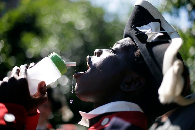 Dressed in a wool uniform, a member of the Plymouth Fife and Drum Corps took a drink near Independence Hall in Philadelphia on July 16, 2013. An excessive heat warning is in effect in Philadelphia and surrounding counties.