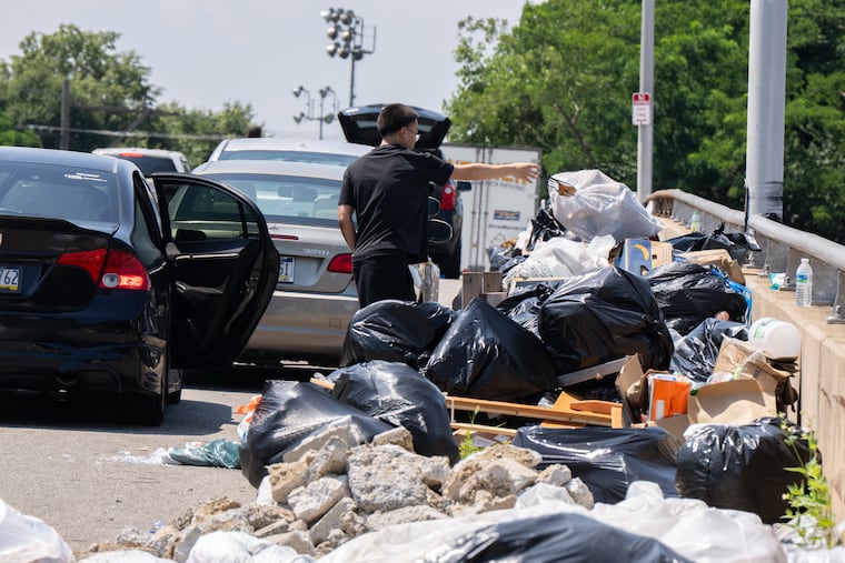 People dump trash on the bridge next to the sanitation center on South 63rd Street in Philadelphia Thursday.