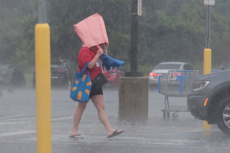 A Deptford Wal-Mart shopper leaves the store with a bag on their head for protection from the heavy rains on Tuesday.