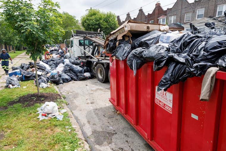 Workers at city dump site, Columbia Avenue and 60th Street load containers with bags of trash.