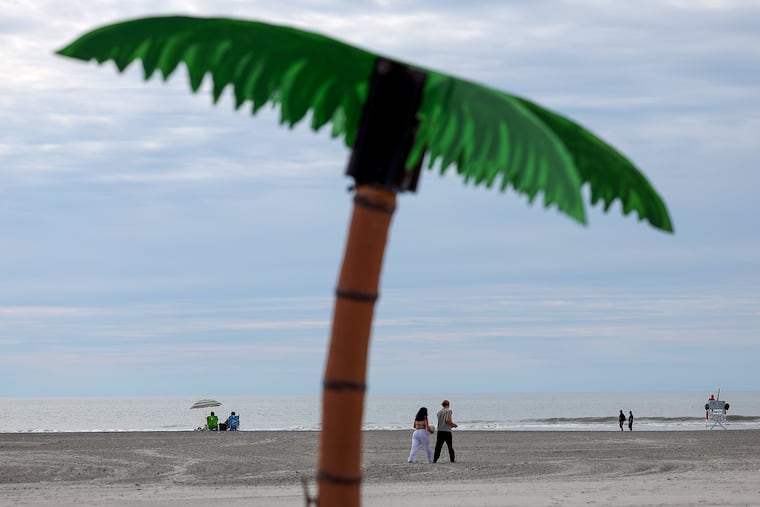A couple walks by a fake palm tree on the beach in Wildwood on Memorial Day.