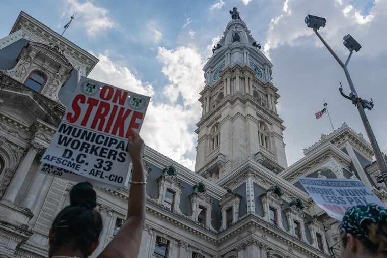 Municipal workers hold up signs at City Hall, Philadelphia, during a workers’ strike on Wednesday, July 2, 2025.