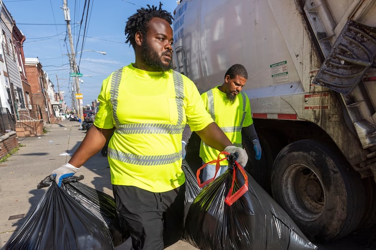 Quamir Anderson and Rashan Purcell (background) work together clearing sidewalks of weekly trash along Ritner Street. Trash pickup is among the city services that would be impacted in a DC 33 strike.